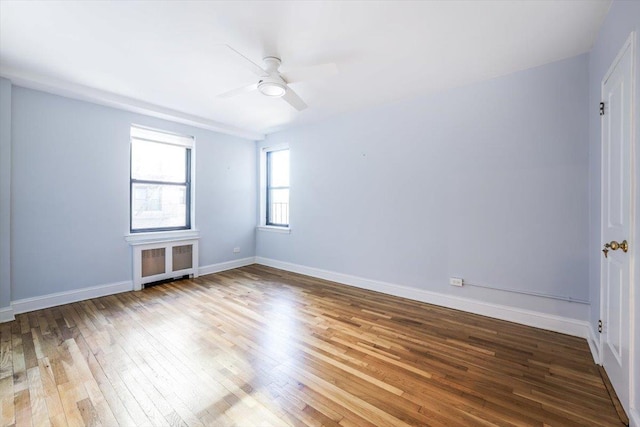 spare room featuring wood-type flooring, ceiling fan, and radiator