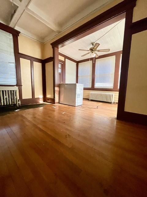 interior space with ceiling fan, beamed ceiling, hardwood / wood-style flooring, and radiator