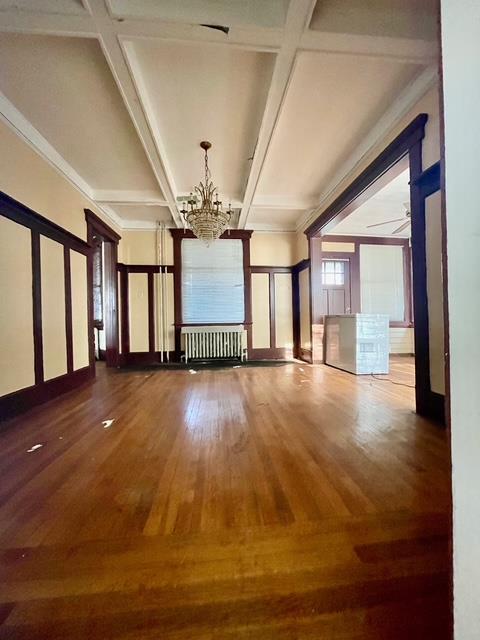 interior space with beamed ceiling, ornamental molding, radiator, coffered ceiling, and a chandelier