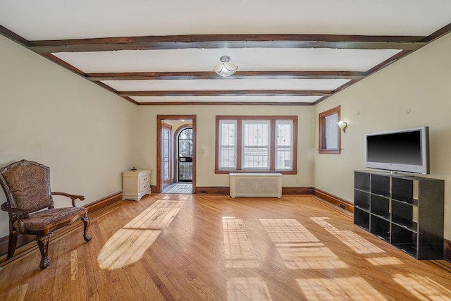 interior space featuring beamed ceiling, radiator heating unit, and light hardwood / wood-style flooring