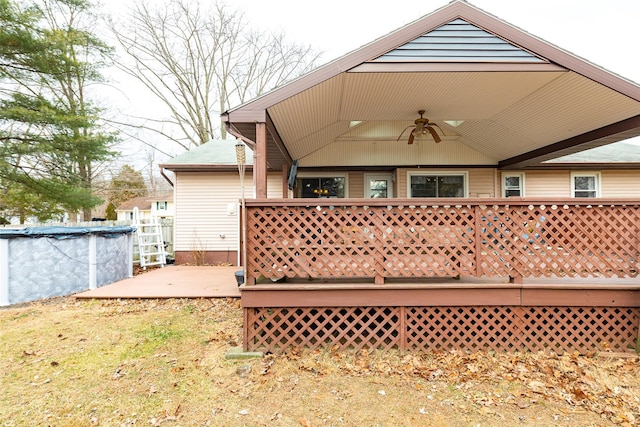 rear view of property with ceiling fan and a pool side deck