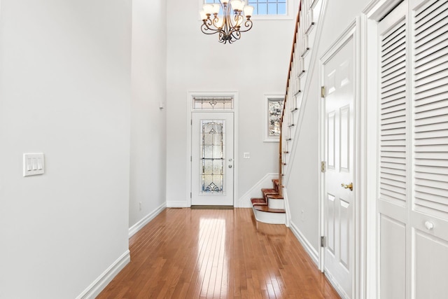 entrance foyer with a towering ceiling, a chandelier, and light hardwood / wood-style flooring