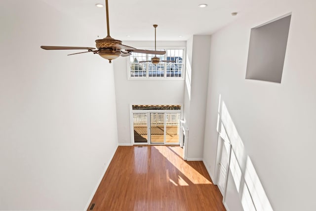 interior space with ceiling fan, a towering ceiling, and light hardwood / wood-style floors