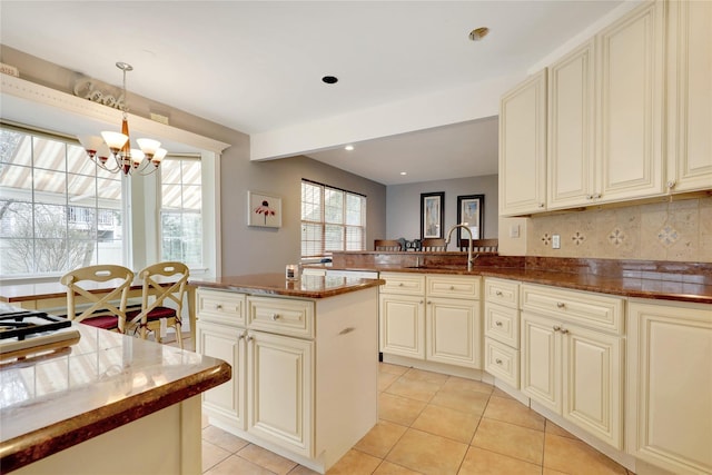 kitchen with light tile patterned floors, cream cabinetry, an inviting chandelier, and pendant lighting