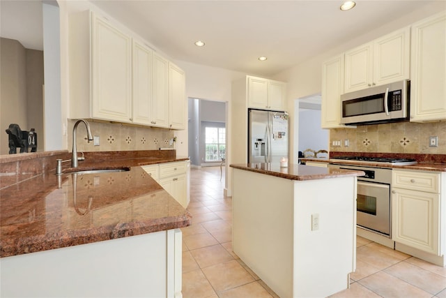 kitchen with sink, appliances with stainless steel finishes, a center island, and dark stone countertops