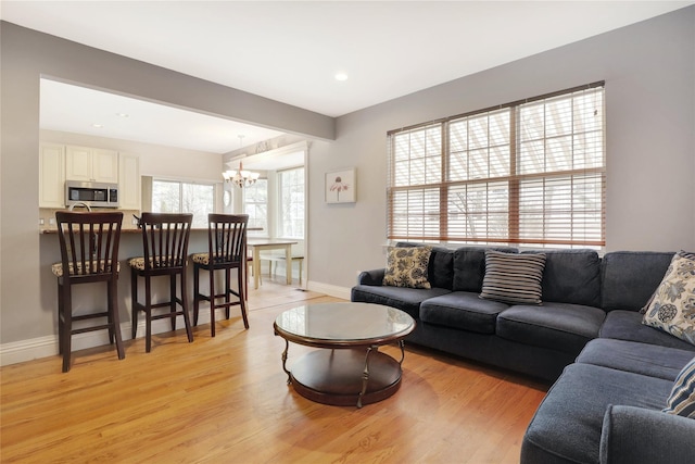 living room with light wood-type flooring and a notable chandelier