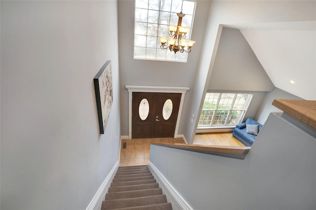 stairway with tile patterned flooring and an inviting chandelier