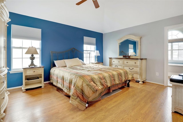 bedroom with ceiling fan, light hardwood / wood-style flooring, and vaulted ceiling