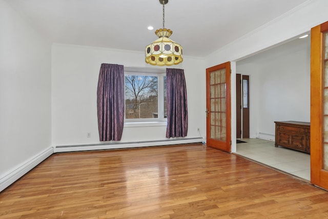 spare room with ornamental molding, baseboard heating, and light hardwood / wood-style floors