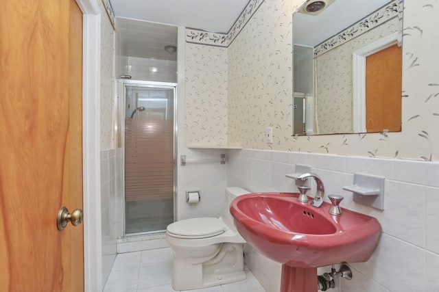 bathroom with toilet, a shower with shower door, sink, tile walls, and tile patterned flooring