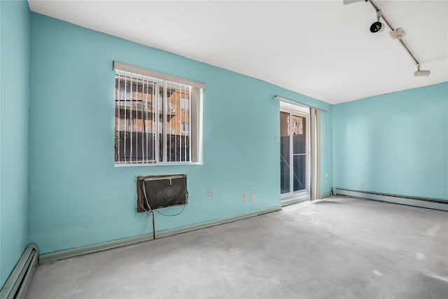 spare room featuring a baseboard heating unit, concrete flooring, and track lighting