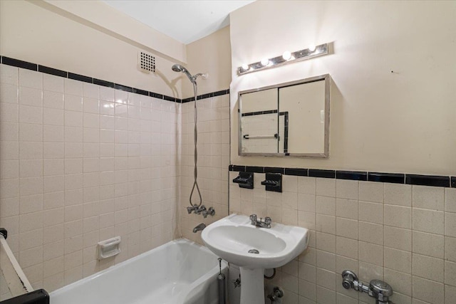 bathroom with sink, tile walls, and tiled shower / bath combo