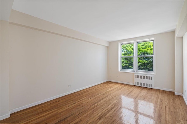 empty room featuring radiator heating unit and light hardwood / wood-style flooring