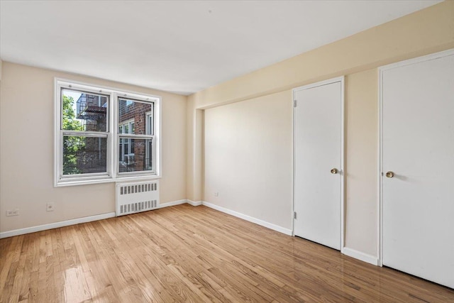 empty room with radiator and light wood-type flooring