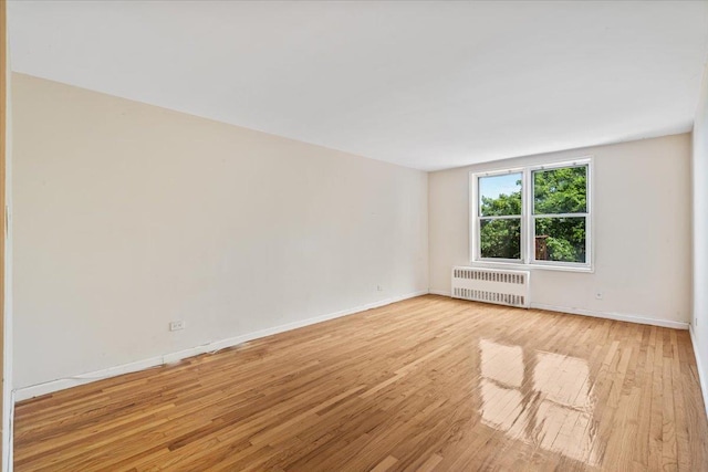 empty room with light wood-type flooring and radiator heating unit