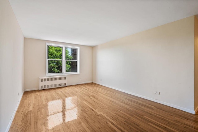 unfurnished room with radiator heating unit and light hardwood / wood-style floors