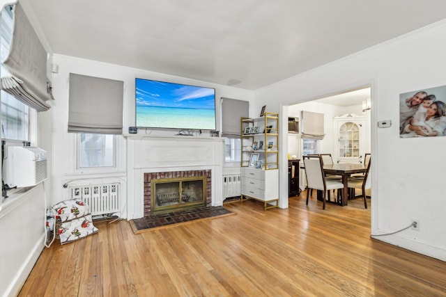 living room with a brick fireplace, hardwood / wood-style floors, radiator heating unit, and cooling unit