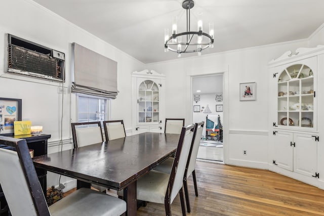 dining space with light wood-type flooring, ornamental molding, and a chandelier