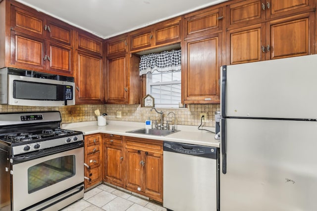 kitchen featuring light tile patterned floors, sink, appliances with stainless steel finishes, and tasteful backsplash