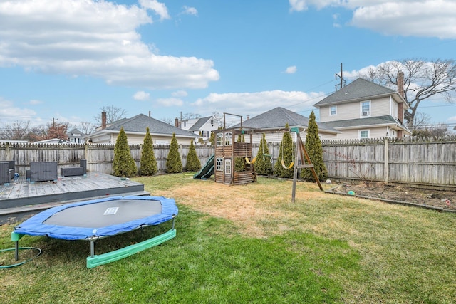 view of yard featuring central air condition unit, a trampoline, a wooden deck, and a playground