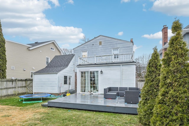 back of property with a trampoline, outdoor lounge area, a lawn, a balcony, and a deck