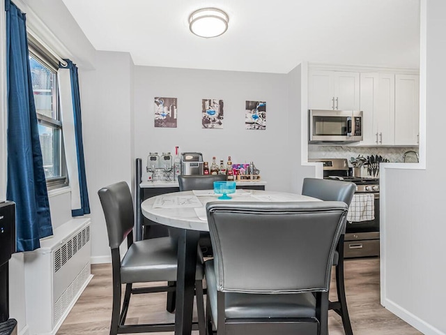 dining room with light hardwood / wood-style floors and radiator heating unit