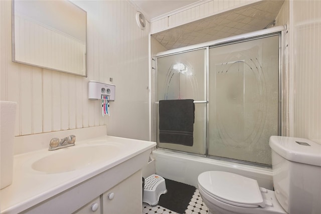 full bathroom with toilet, vanity, wood walls, and bath / shower combo with glass door