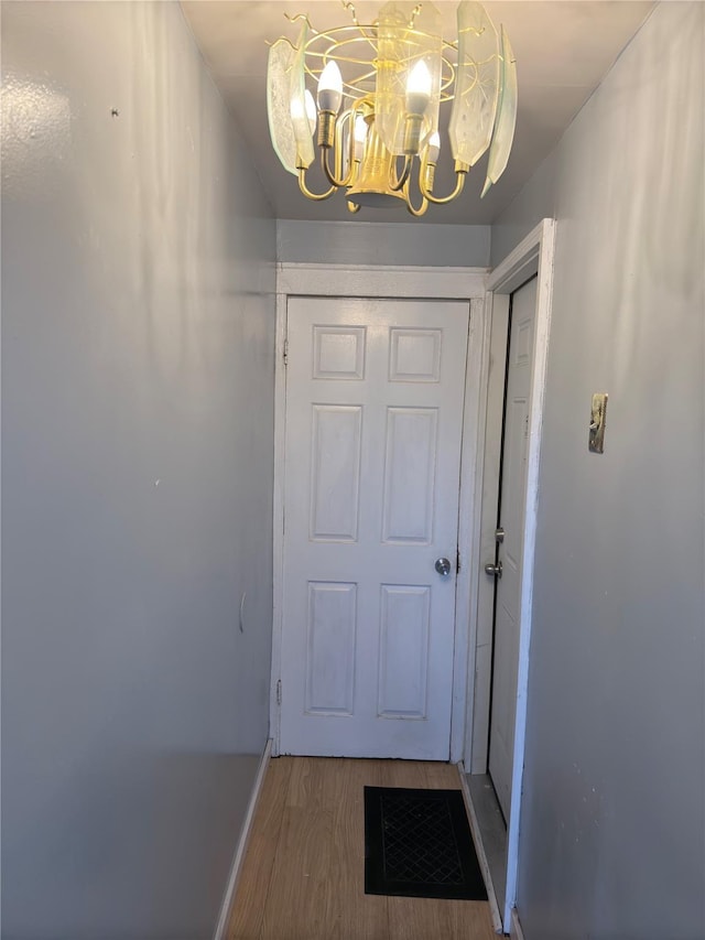 doorway to outside featuring wood-type flooring and a notable chandelier