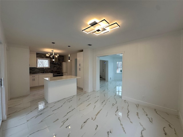 kitchen with marble finish floor, white cabinets, a kitchen island, and backsplash