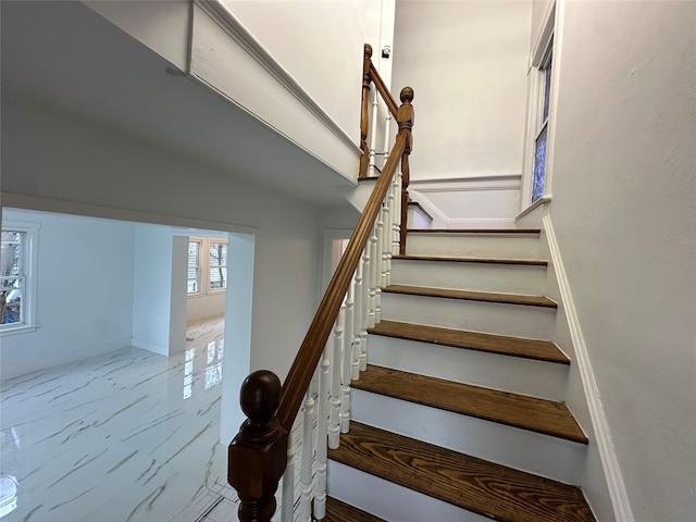 stairway with marble finish floor and baseboards