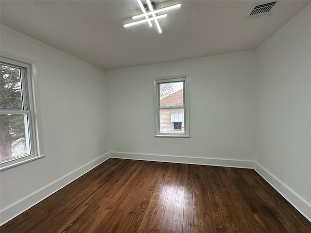 spare room with visible vents, baseboards, and dark wood finished floors