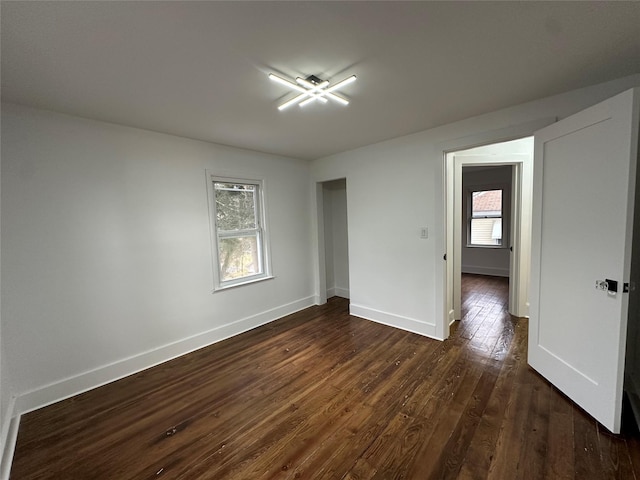 spare room featuring dark wood-type flooring and baseboards