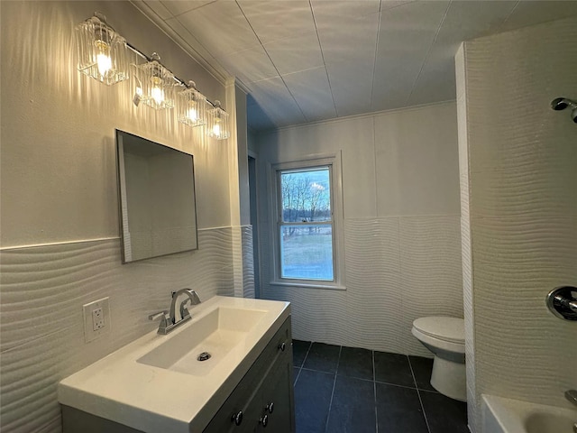 bathroom featuring toilet, vanity, tile walls, tile patterned floors, and a tub to relax in