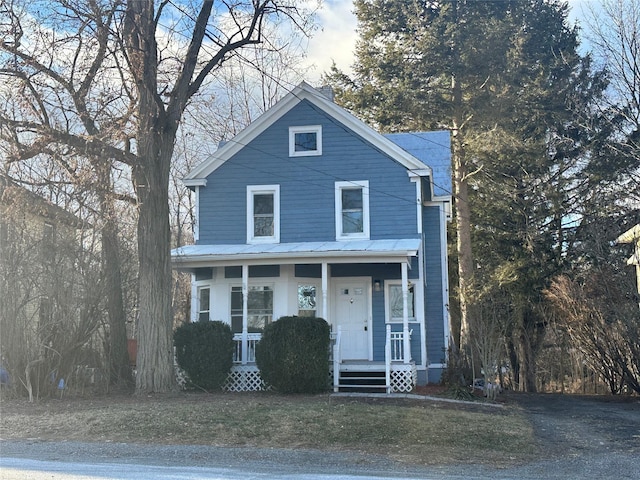 view of front of property with metal roof, a porch, and a front lawn