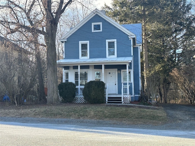 view of front of home featuring covered porch, metal roof, and a front yard