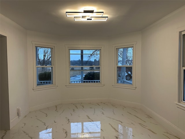 unfurnished room featuring marble finish floor and baseboards