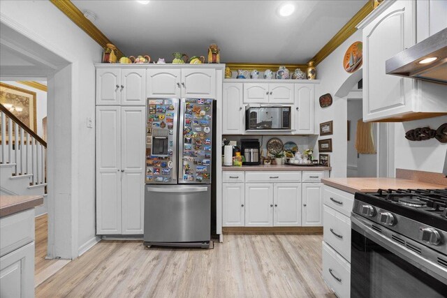 kitchen featuring crown molding, light hardwood / wood-style flooring, white cabinetry, stainless steel appliances, and extractor fan