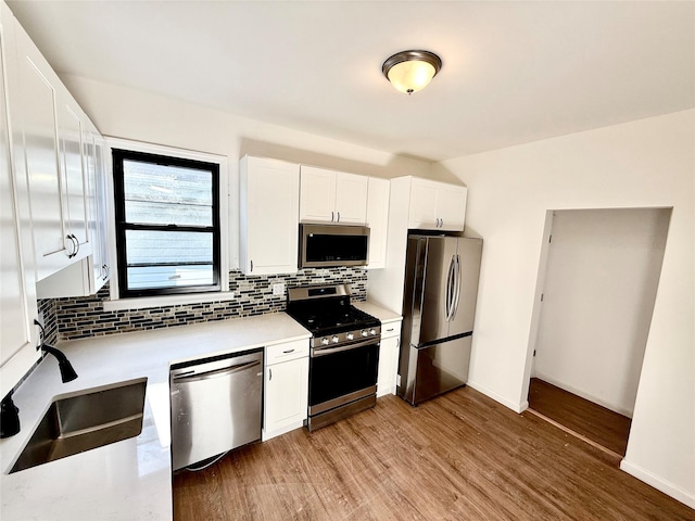 kitchen featuring appliances with stainless steel finishes, white cabinetry, tasteful backsplash, and sink