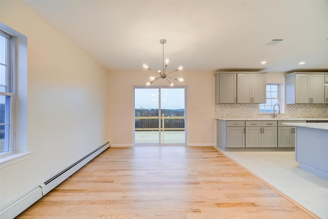 kitchen with decorative light fixtures, decorative backsplash, a wealth of natural light, gray cabinetry, and baseboard heating