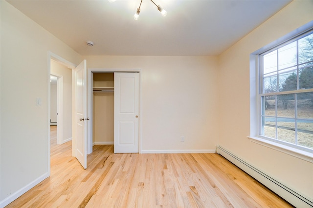 unfurnished bedroom with light hardwood / wood-style floors, baseboard heating, and a closet