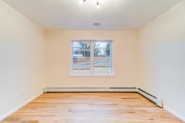 empty room with light hardwood / wood-style floors and a baseboard heating unit