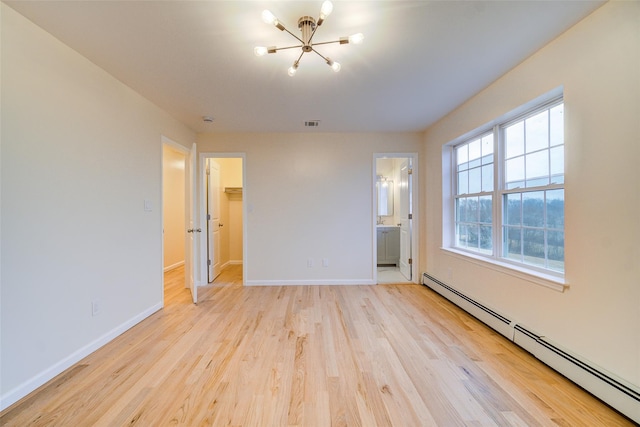 unfurnished bedroom featuring a baseboard heating unit, light wood-type flooring, connected bathroom, a walk in closet, and a closet