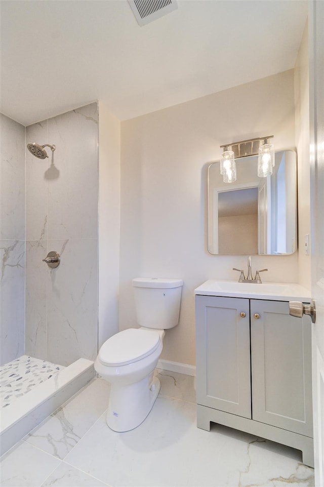 bathroom with tiled shower, vanity, and toilet