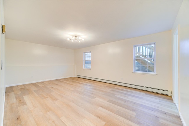 spare room with a baseboard heating unit, plenty of natural light, a notable chandelier, and light hardwood / wood-style floors