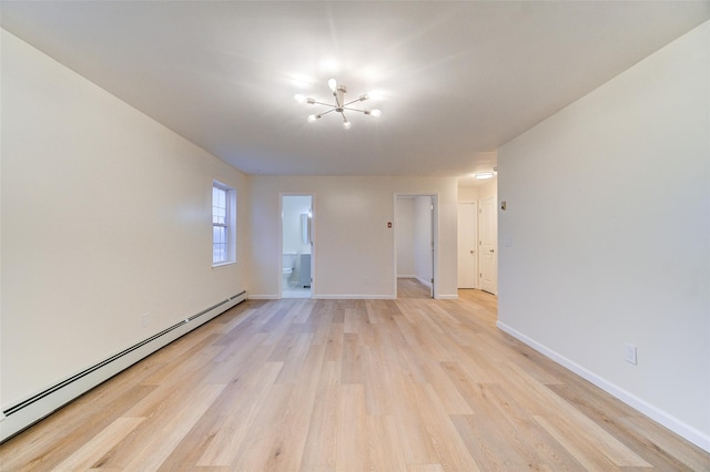 spare room featuring a baseboard heating unit and light wood-type flooring