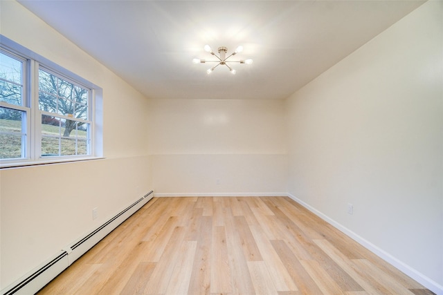 unfurnished room featuring a baseboard heating unit, an inviting chandelier, and light hardwood / wood-style floors