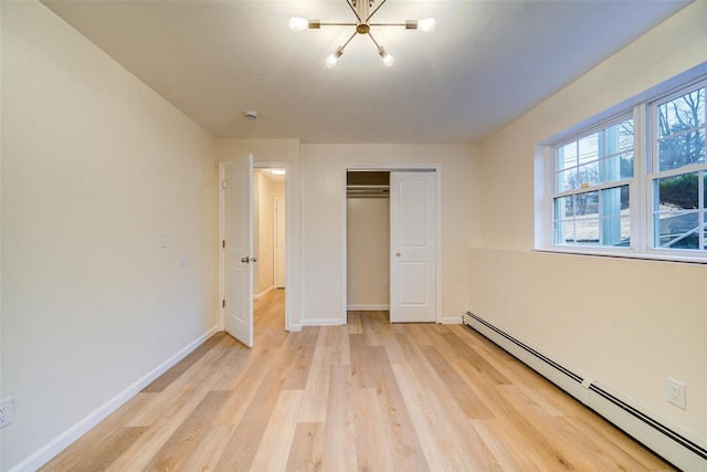 unfurnished bedroom with baseboard heating, a closet, an inviting chandelier, and light hardwood / wood-style flooring