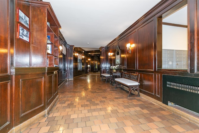 interior space with radiator heating unit, wooden walls, crown molding, and mail boxes