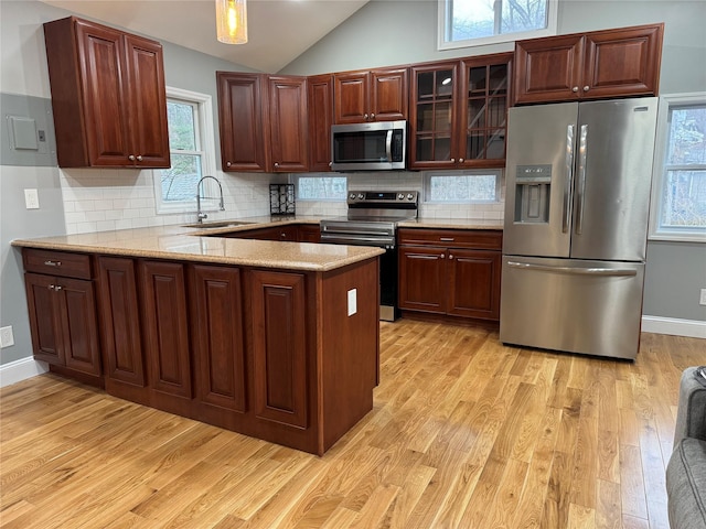 kitchen featuring light stone countertops, lofted ceiling, stainless steel appliances, sink, and light wood-type flooring