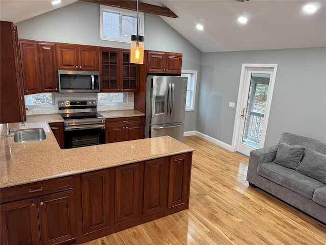 kitchen with tasteful backsplash, pendant lighting, lofted ceiling with beams, sink, and appliances with stainless steel finishes